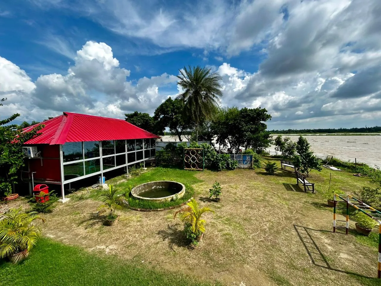 Aerial view of Tarangini Resort — red-roofed cottages amid green and gold fields